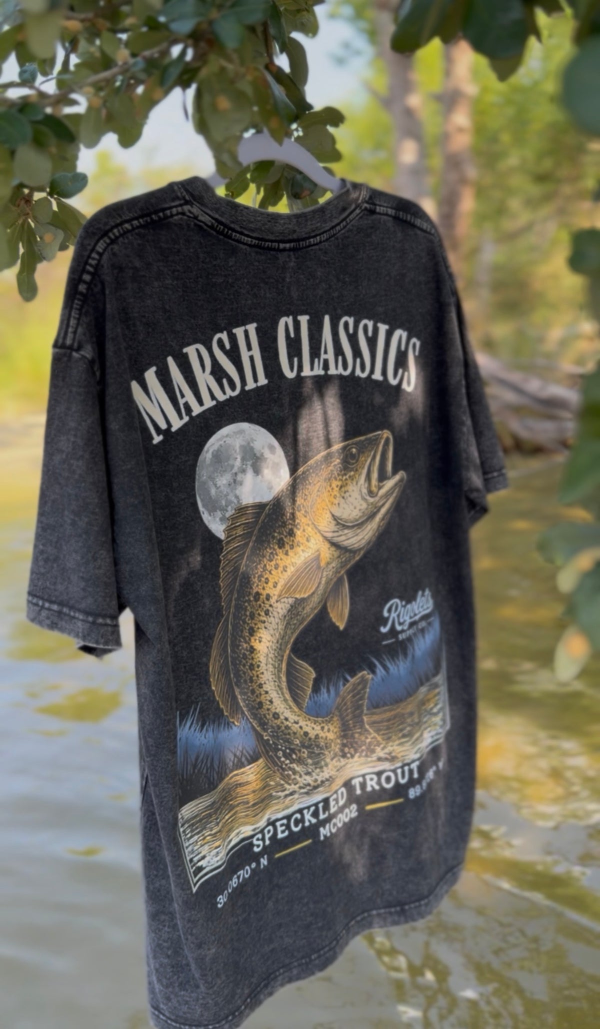 Oversized unisex drop should fishing t shirt featuring the Rigolets Supply Logo, and a large speckled trout under a full moon with the text 'MARSH CLASSICS' at the top and 'speckled trout mc002" at the bottom.